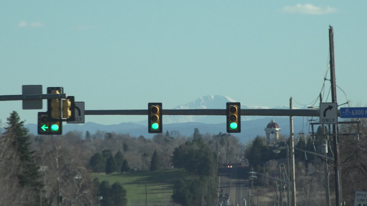 Traffic signals and road framed against a pale sky and mountains.