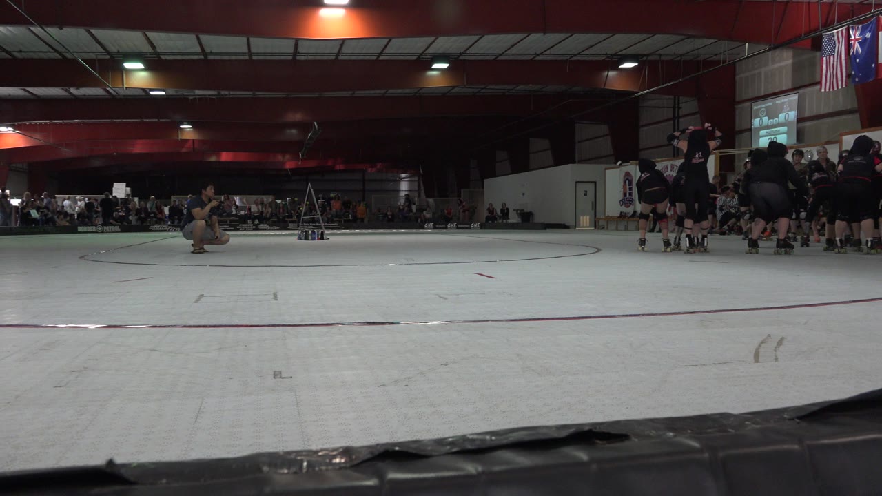 Low view across a roller derby rink with skaters grouped at the right edge.