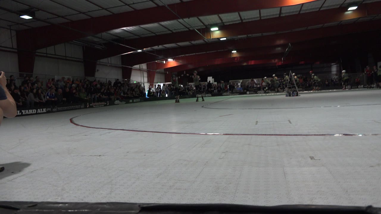 Wide indoor rink with spectators and distant skaters