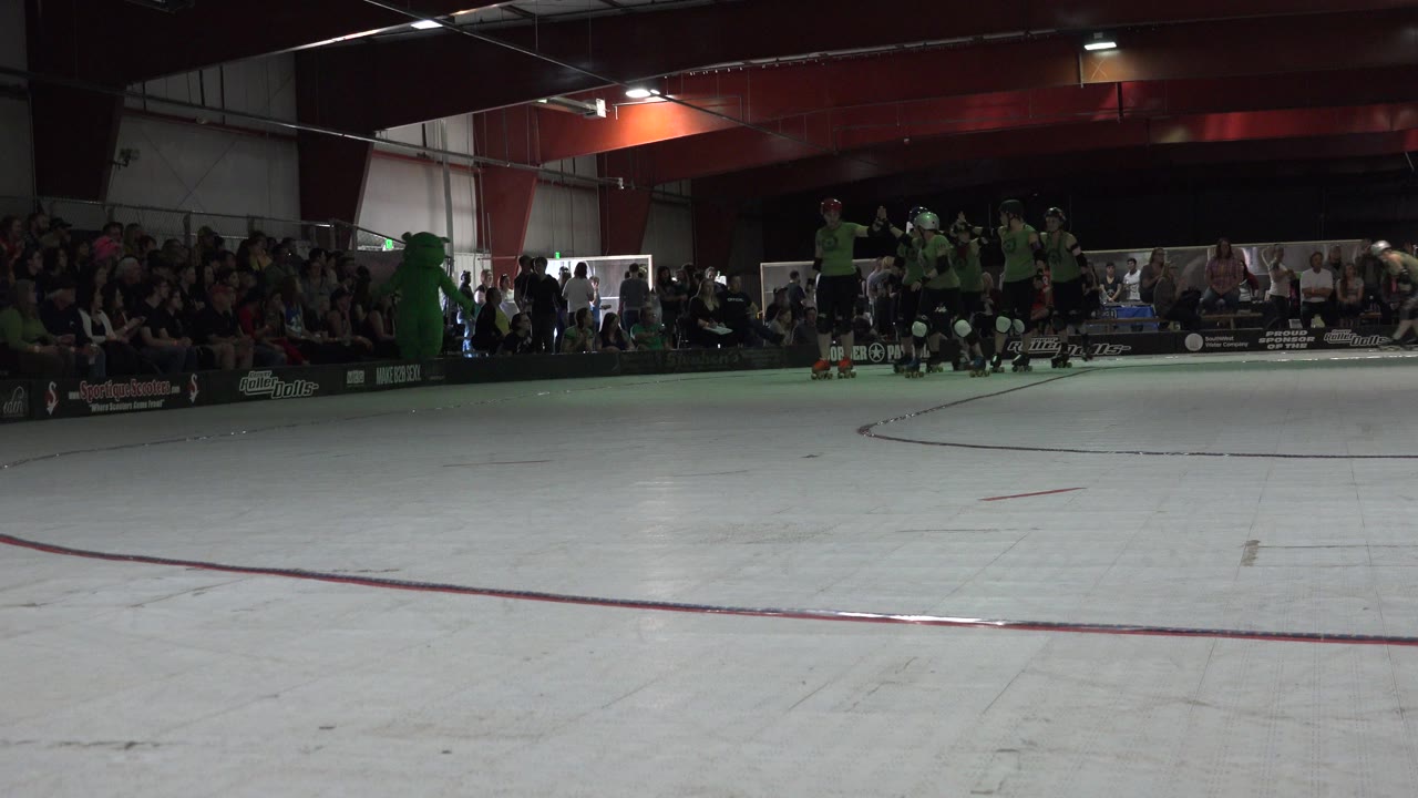 Helmeted skaters wait near the boards on an indoor court.