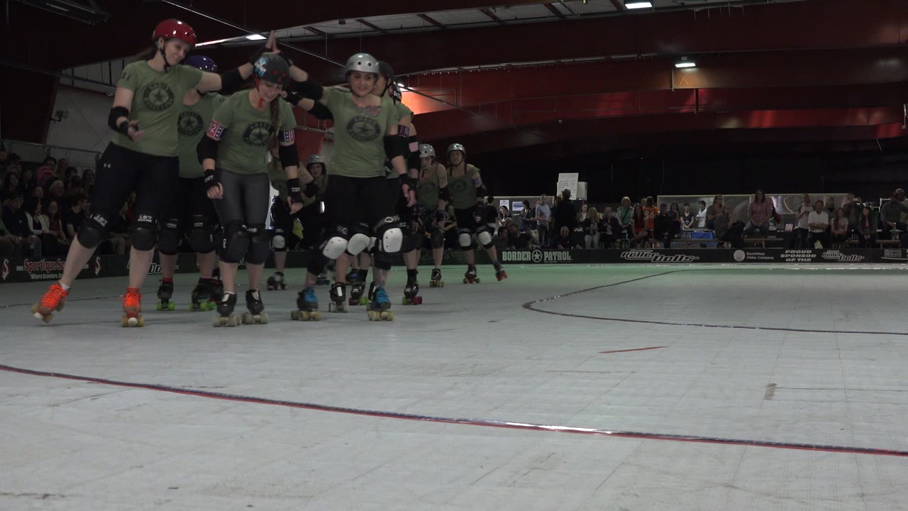 In Denver, Colorado, the same group of skaters stays near the left side of the frame as the rink floor and seated audience remain visible in the background.