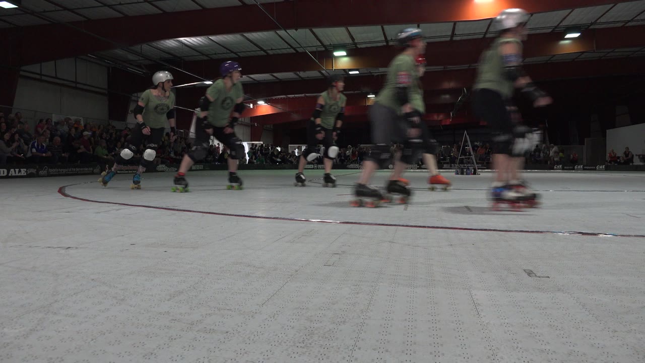 At 0:01 in Denver, Colorado, several padded skaters pass through the upper frame while the pale rink floor fills most of the foreground.