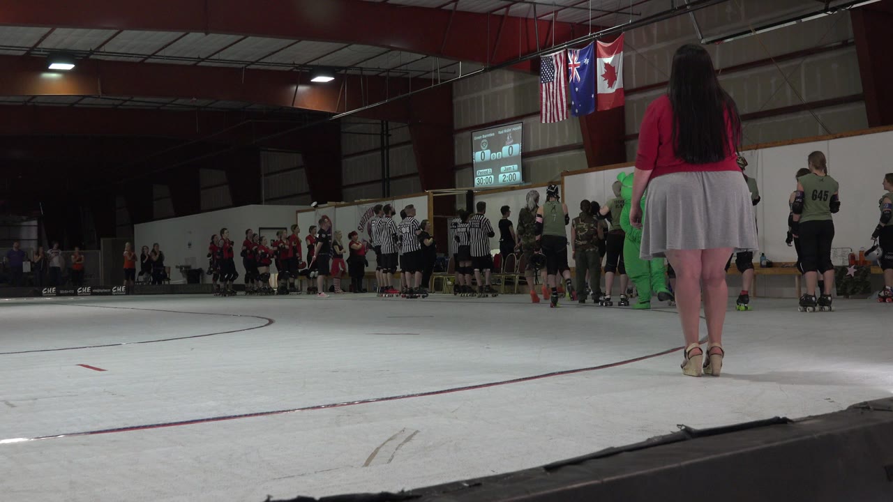 Woman in red shirt standing on an indoor roller derby rink.