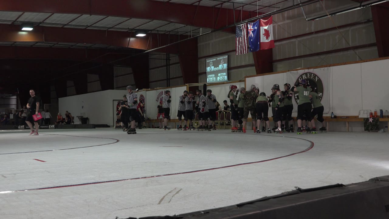 Officials and players stand beside the indoor rink wall.