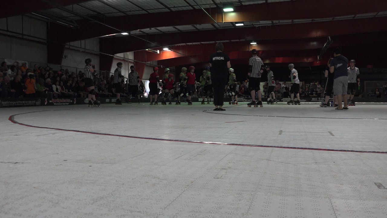 Low view of an indoor roller rink with skaters and spectators.