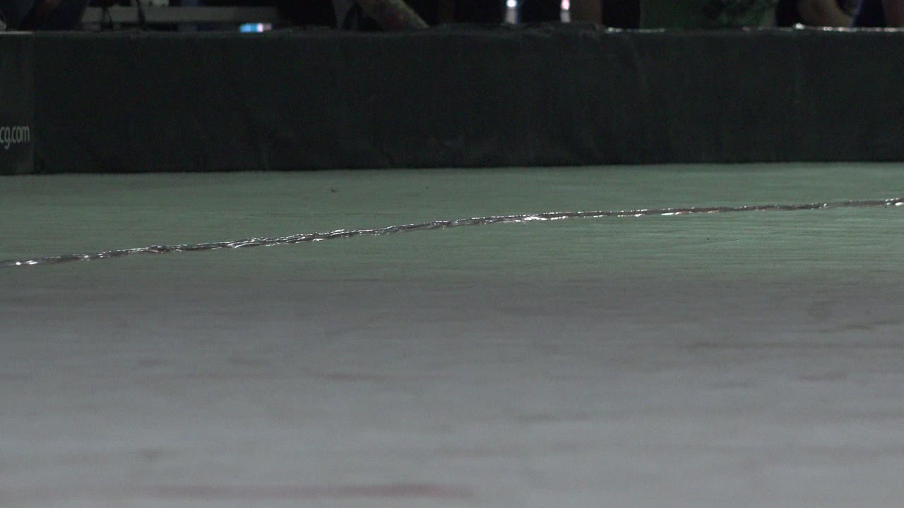 Low view of a cracked green roller rink floor and dark barrier.