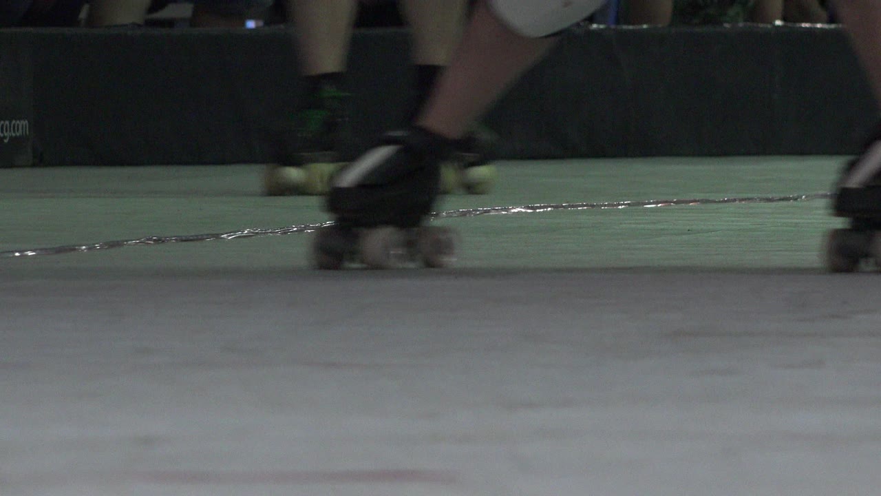 Multiple skaters' feet pass through the frame in Denver, with black quad skates in front and additional wheels blurred in the background.