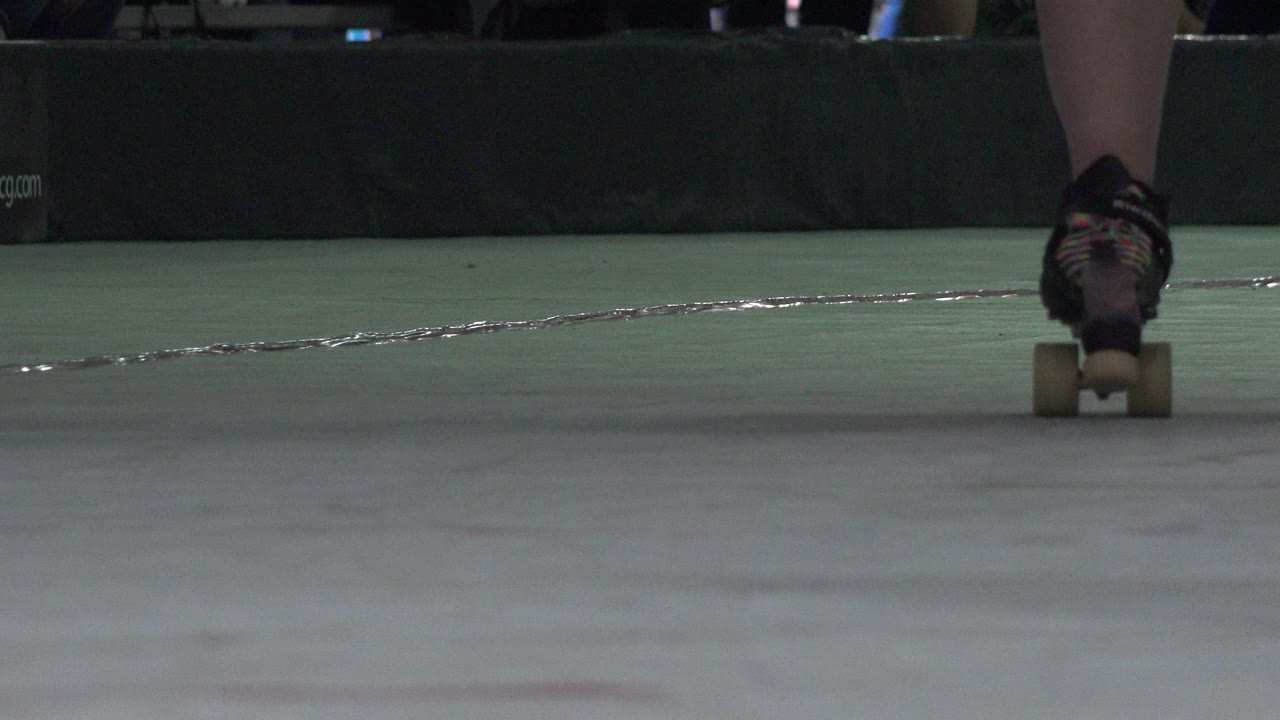 Roller skate centered on an indoor rink floor.