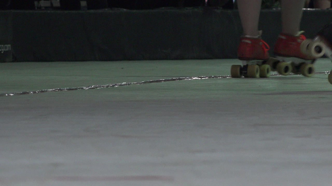 Red quad roller skates on a green indoor floor.
