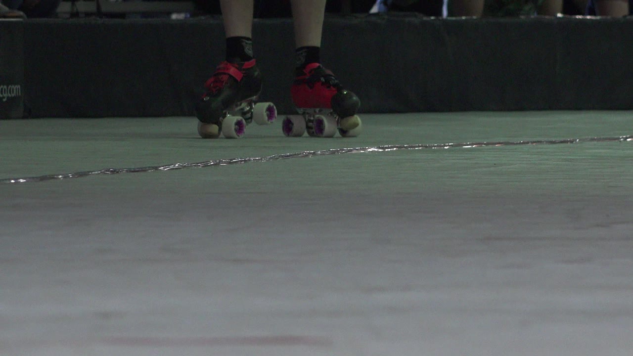 Black and red roller skates on a pale green floor.