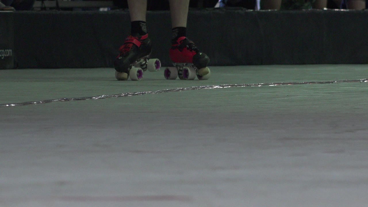 At 0:01, the skates remain near the dark padded barrier while the pale green floor fills most of the foreground in this Denver, Colorado clip.