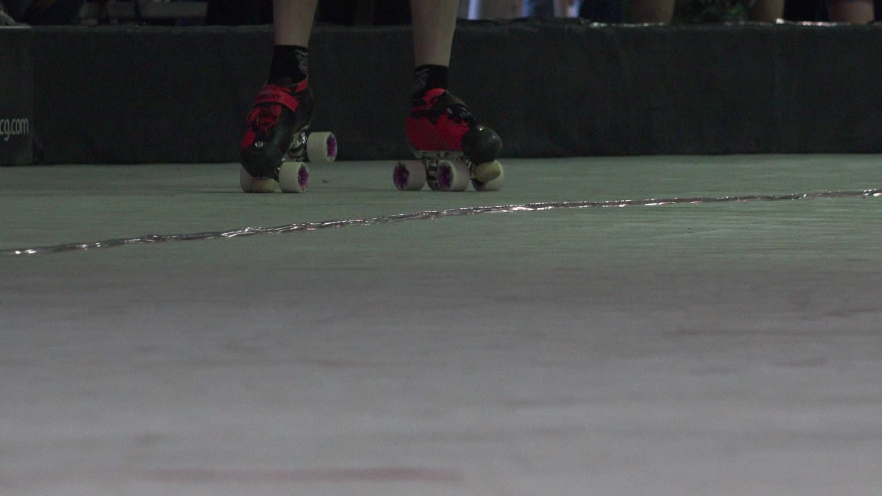 At 0:01, the skater's wheels and toes remain near the upper frame while the green-gray floor and a reflective seam line dominate the Denver 2015 shot.