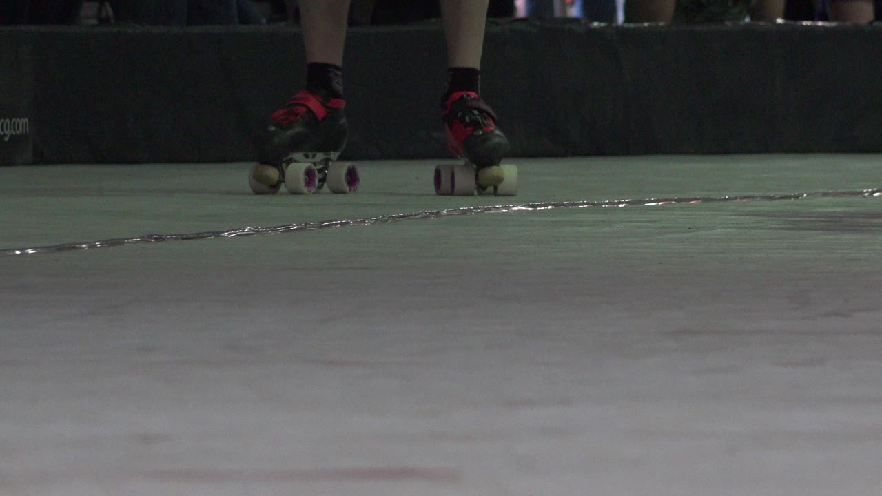 Low view of roller skates near a rink barrier.