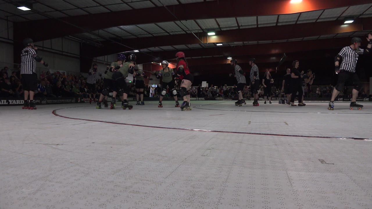 Roller skaters and striped referees gather on an indoor rink.
