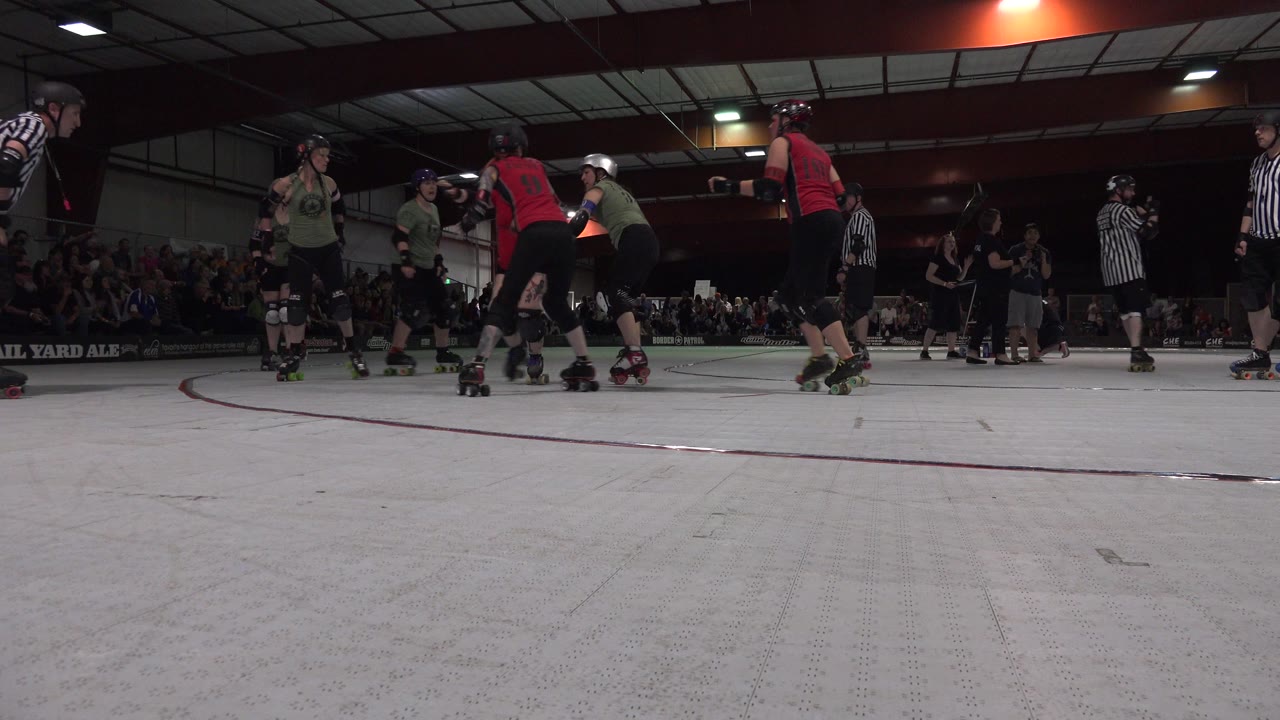 Roller skaters and referees on an indoor rink.