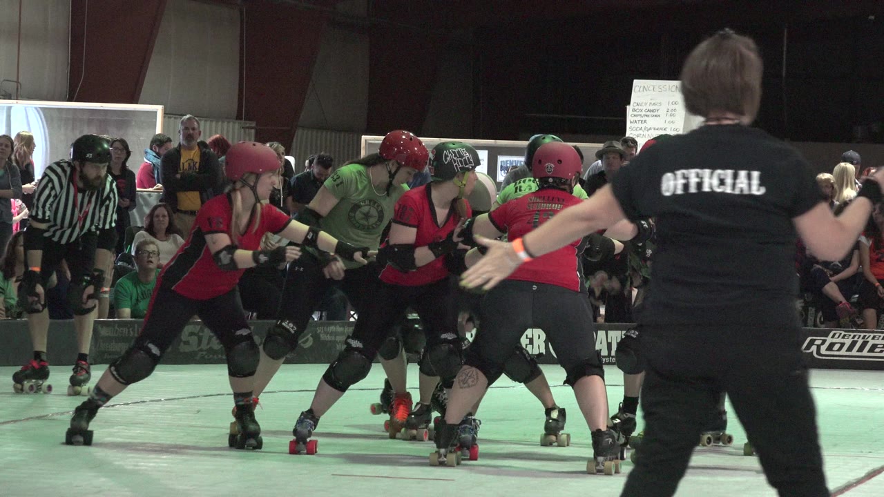 Roller derby pack skates near an official at rinkside.