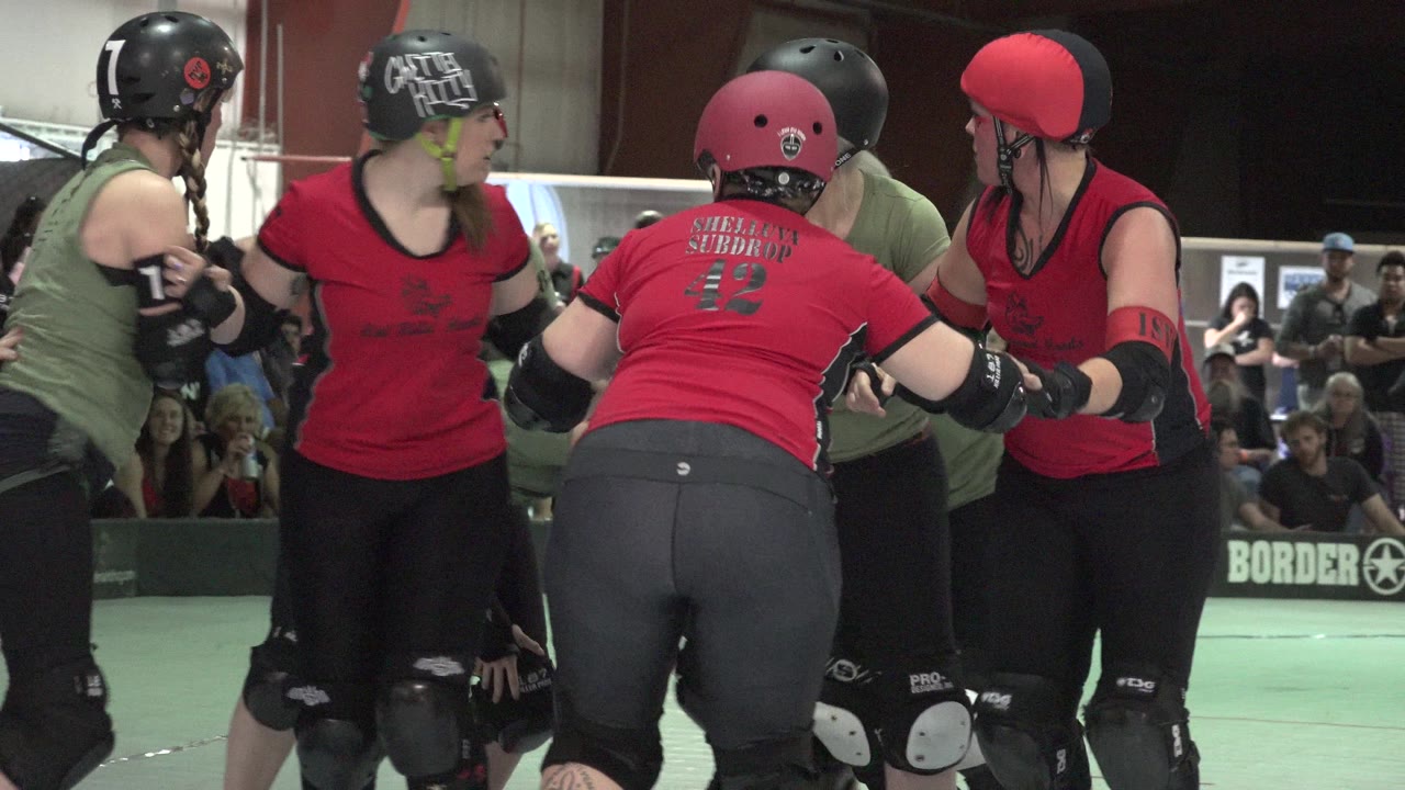 A similar Denver rink-side view shows red-uniformed blockers and green-uniformed skaters pressing shoulder to shoulder, with a barrier sign and seated spectators in the background.