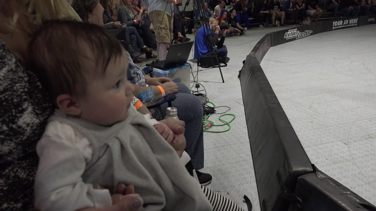 Baby in a woman's lap beside an indoor event barrier.