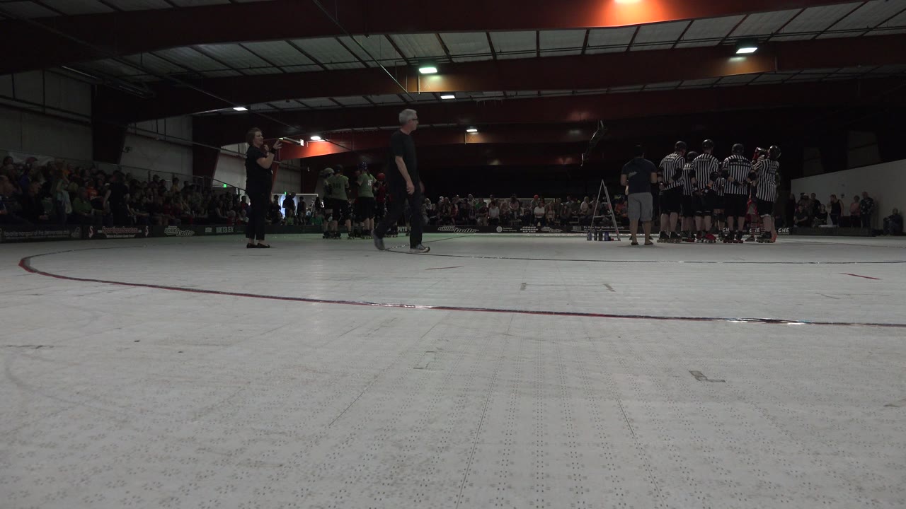 Low gym floor view with teams and spectators in the background.