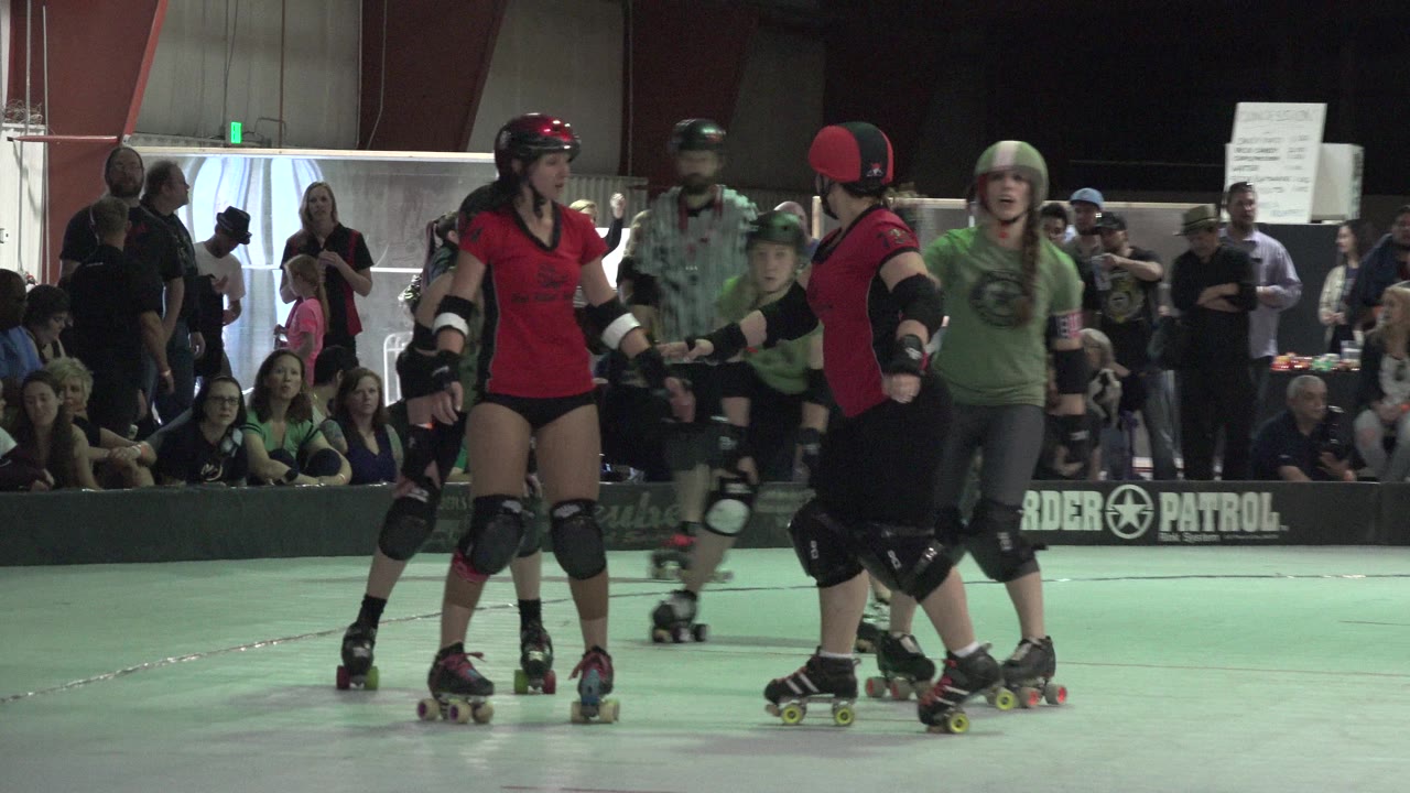 Roller derby skaters in red and green on an indoor track