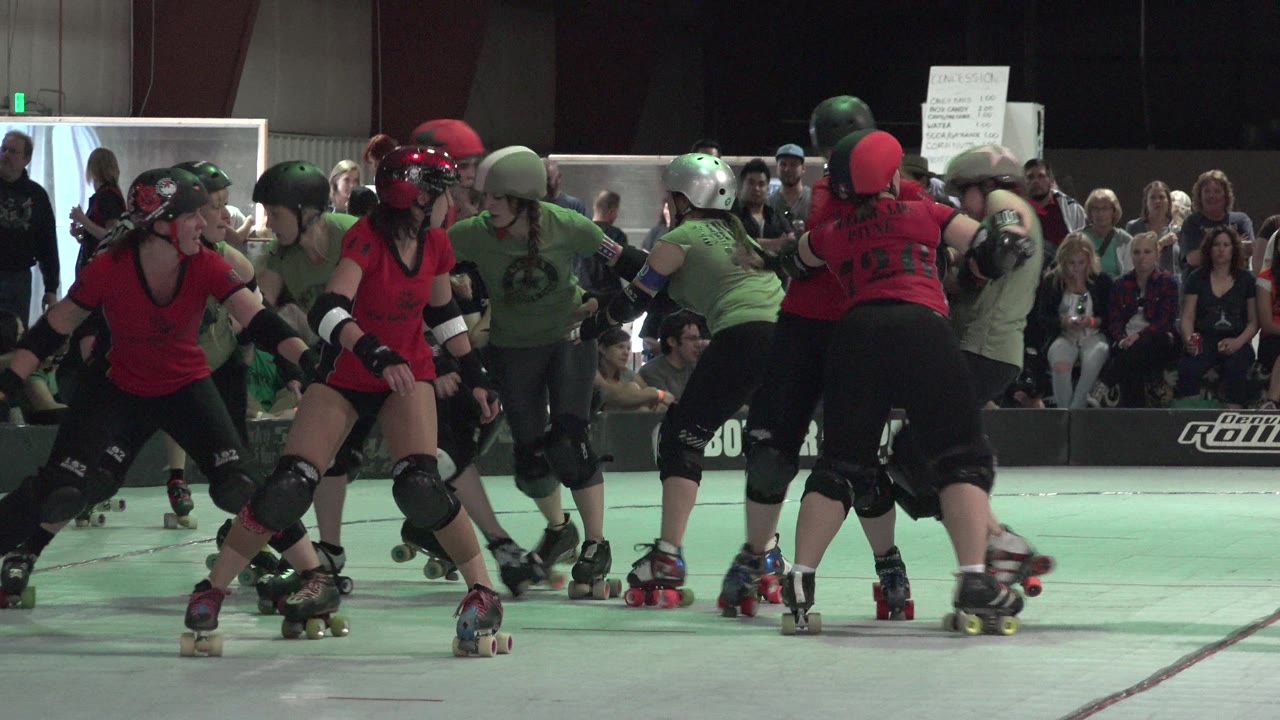Roller derby players skate across the rink while spectators watch.