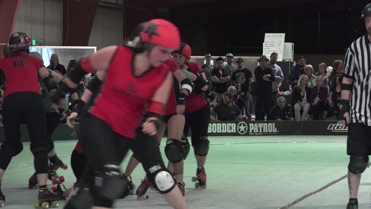 Roller derby skaters in red uniforms pass close to the camera.