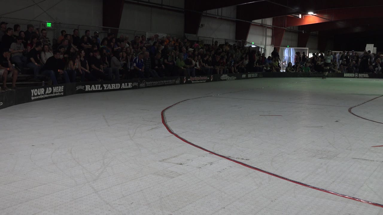 Indoor skating floor with red line and crowded bleachers across the rink.