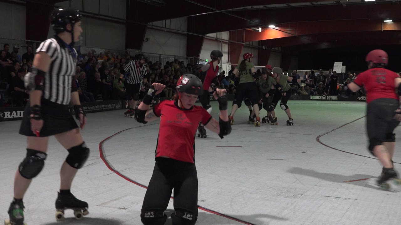 Roller derby skater in red near a referee on a white rink.
