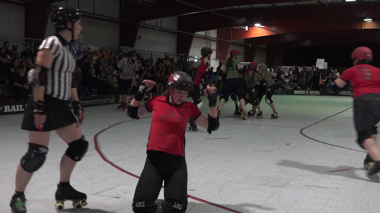 At 0:01 in Denver, the red-uniformed skater is centered near the foreground while a referee and several skaters occupy the midground of the indoor rink.