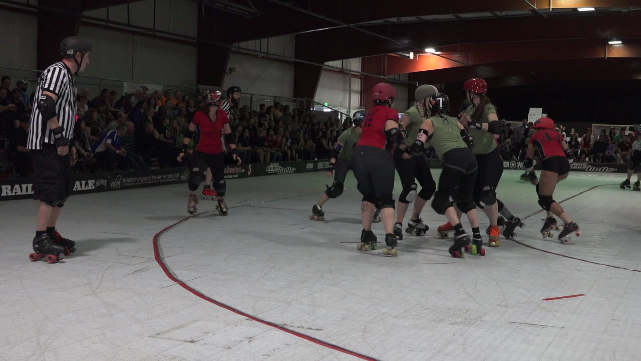 One second into the Denver, Colorado footage, players in red and olive uniforms skate in a tight pack while a referee watches from the left side and spectators line the far wall.