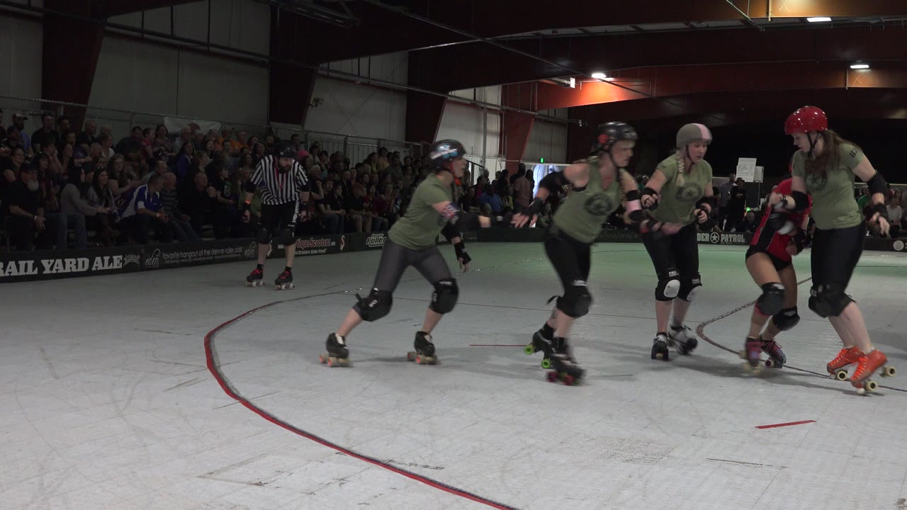 Roller derby skaters bunch together on an indoor rink.