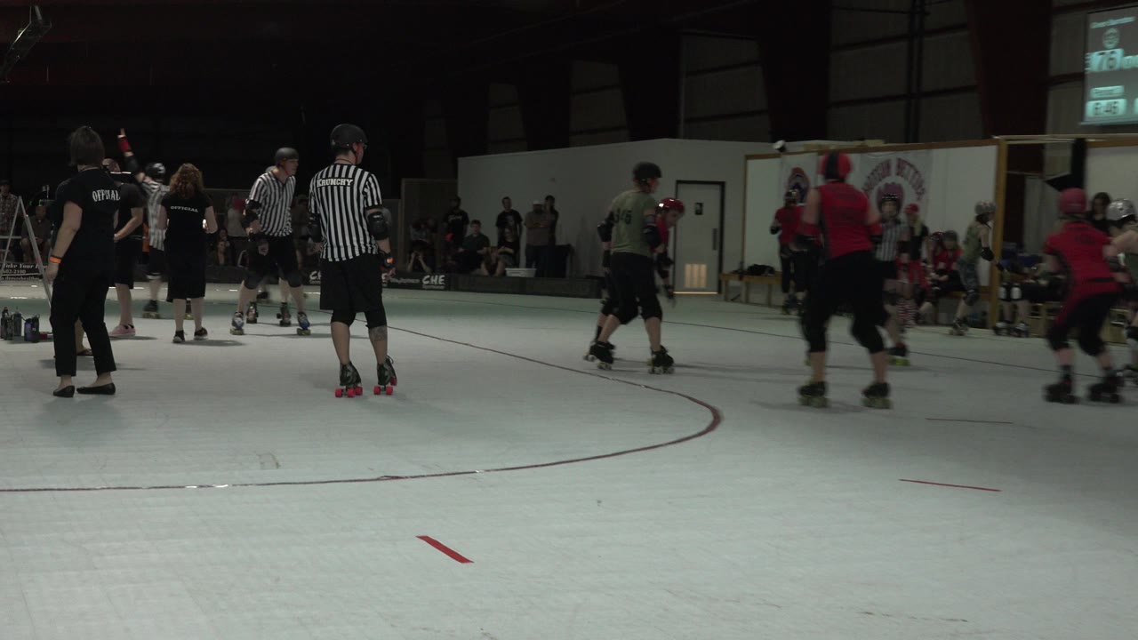 Youth hockey players and referees on an indoor rink.