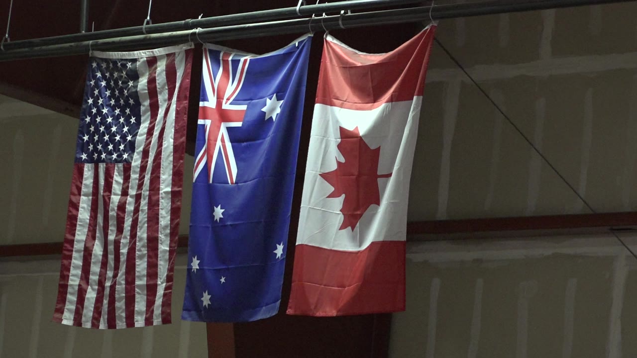 USA, Australia, and Canada flags hanging from a metal rail.