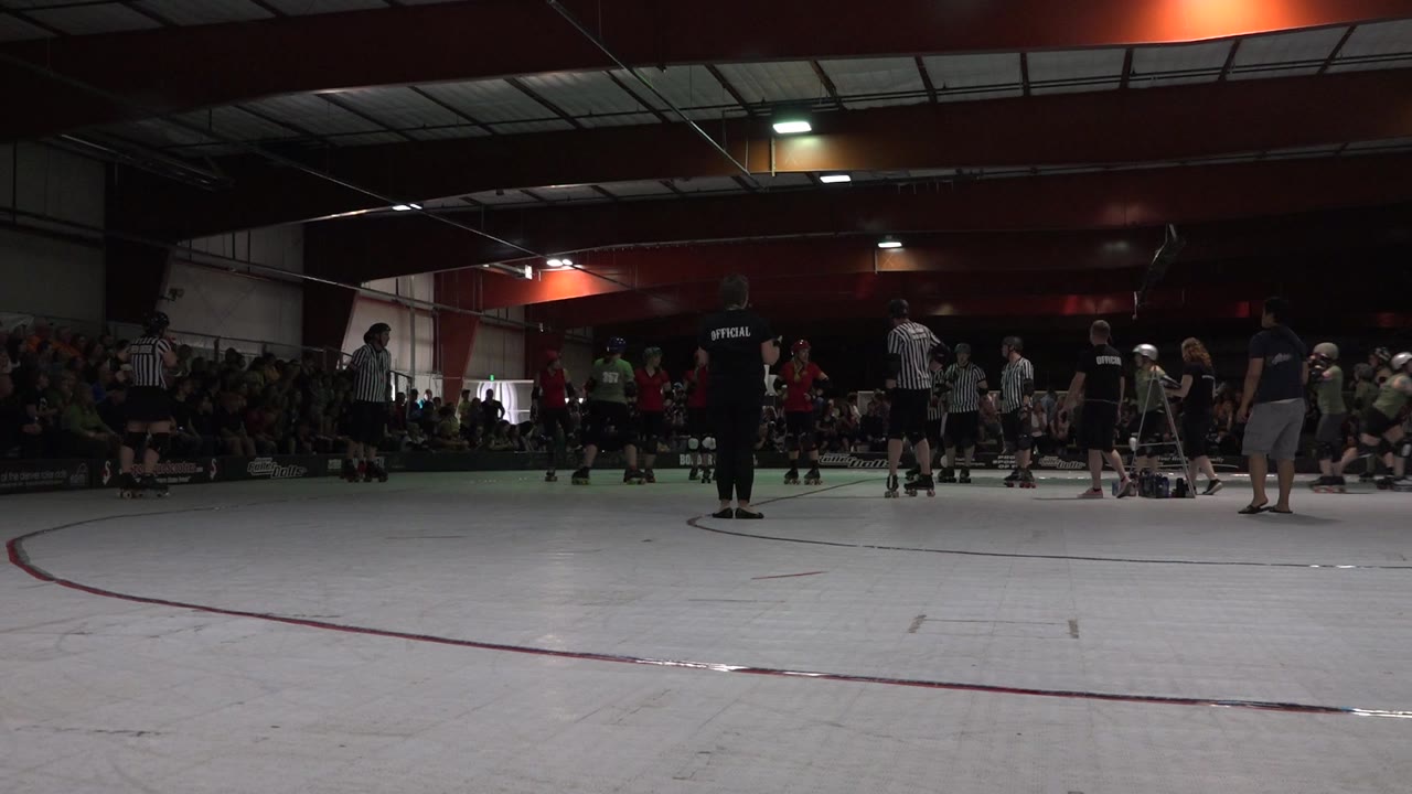 Skaters and officials gather on an indoor roller rink.