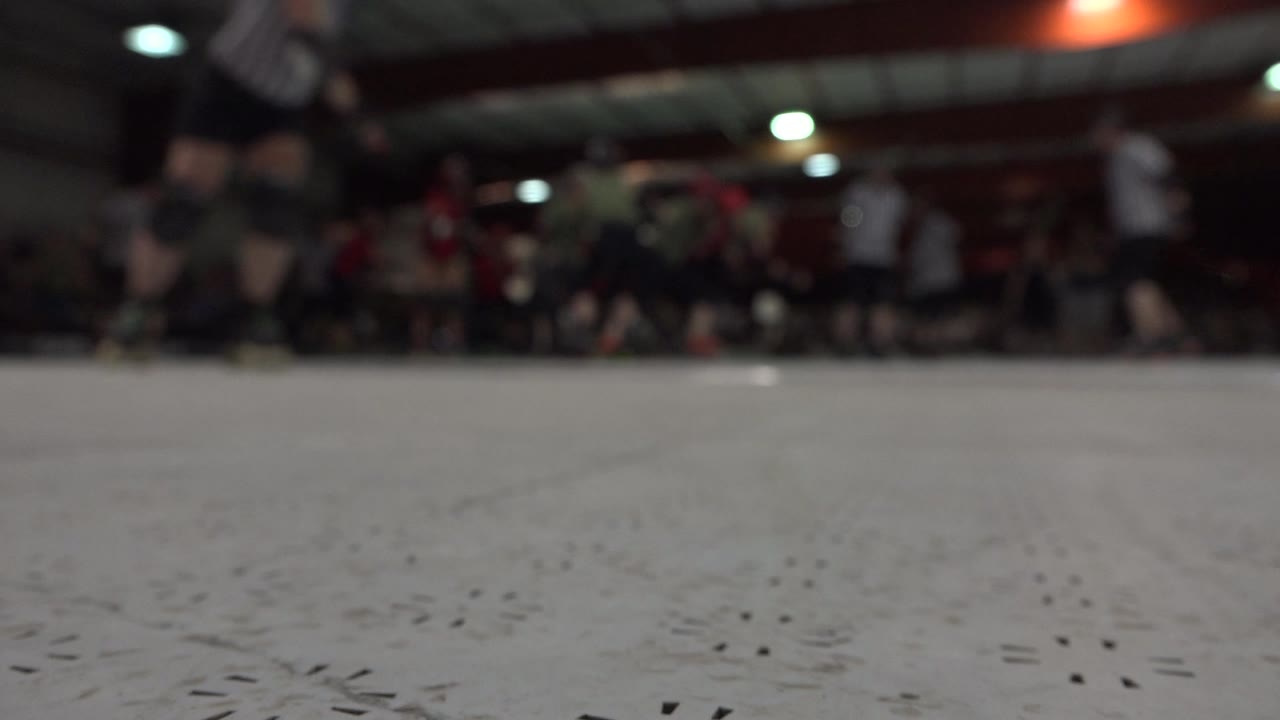Low view of an indoor rink with blurred players in the background.