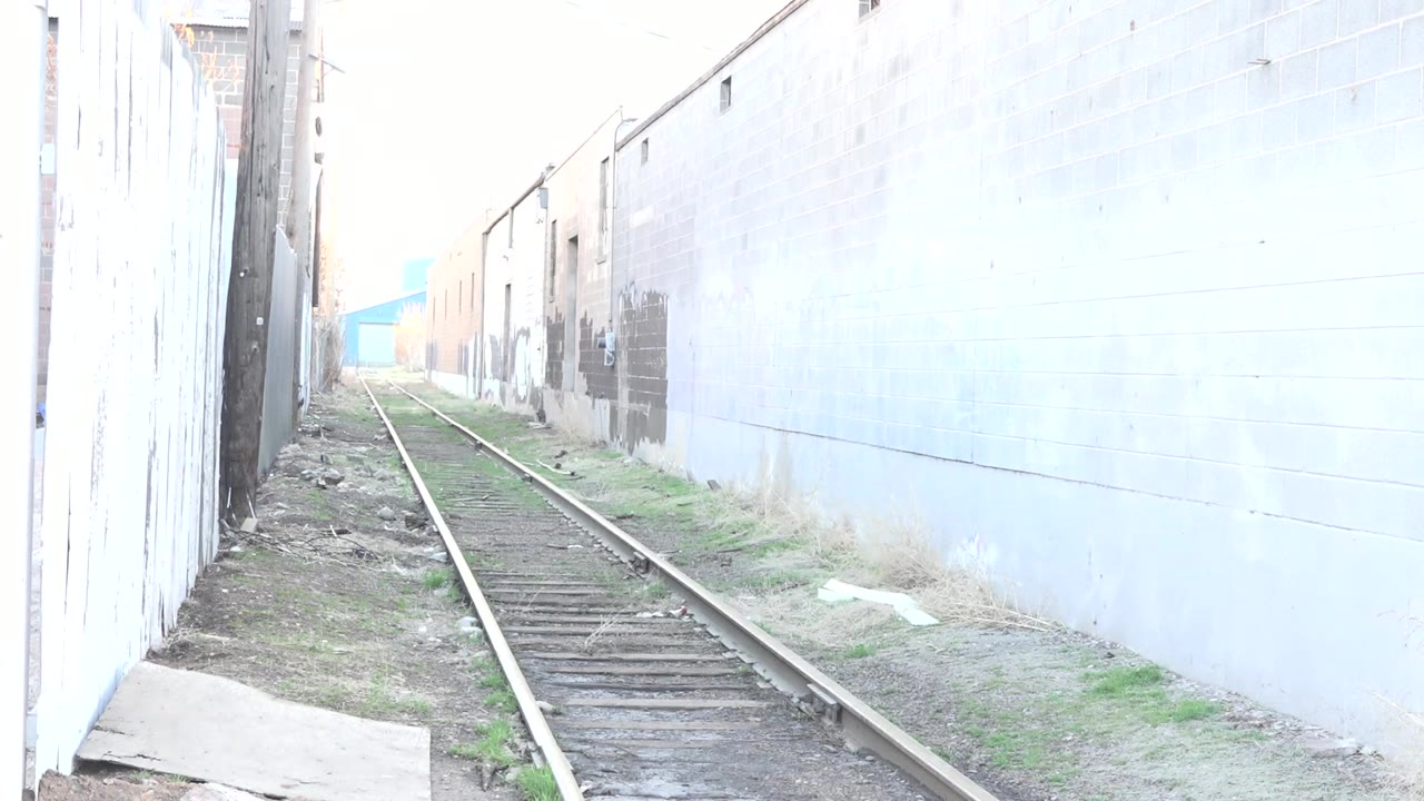 Empty railroad tracks between bright industrial walls.
