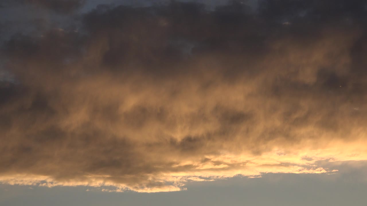 Denver, Colorado dusk sky with dark cloud cover, a warm gold band near the horizon, and no visible people at the start of the clip.