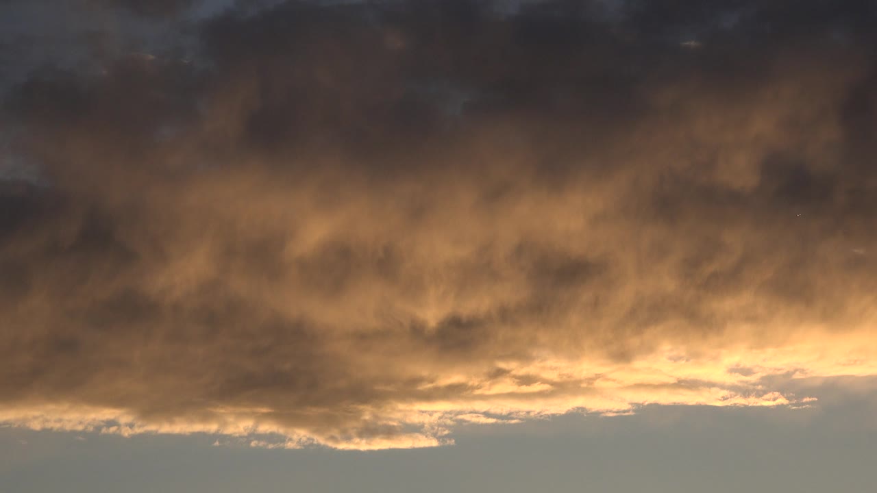 Opening frame of Denver, Colorado sky footage showing a dark cloud bank above a warm orange glow near the horizon, with no visible people.