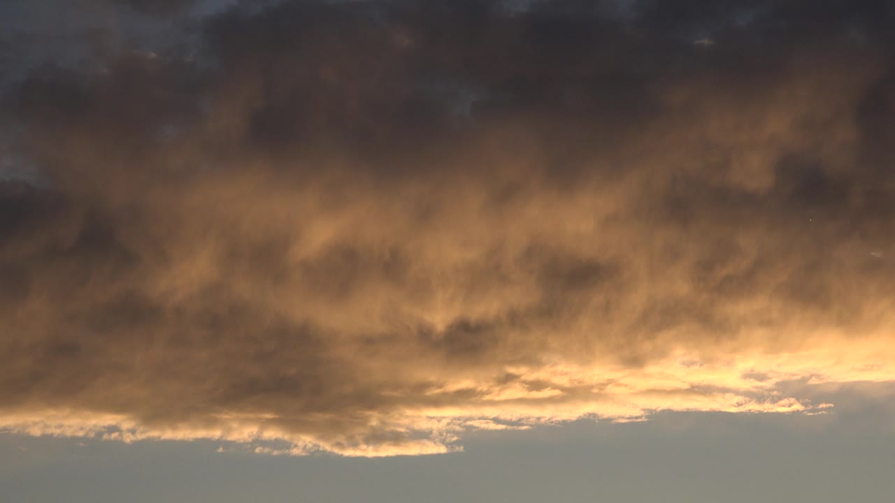 Dark upper cloud layer above a bright sunset glow