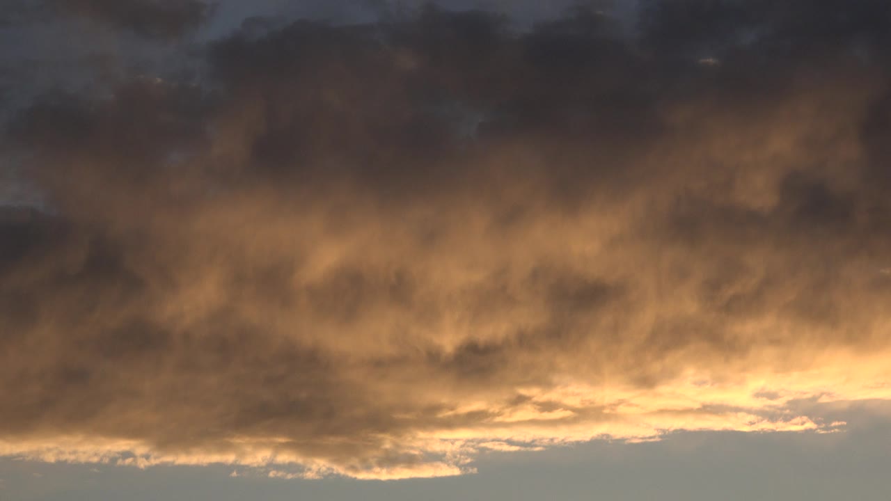 At 0:00 in Denver, orange light glows beneath a dense gray cloud layer with a muted sky band along the bottom and no visible people.