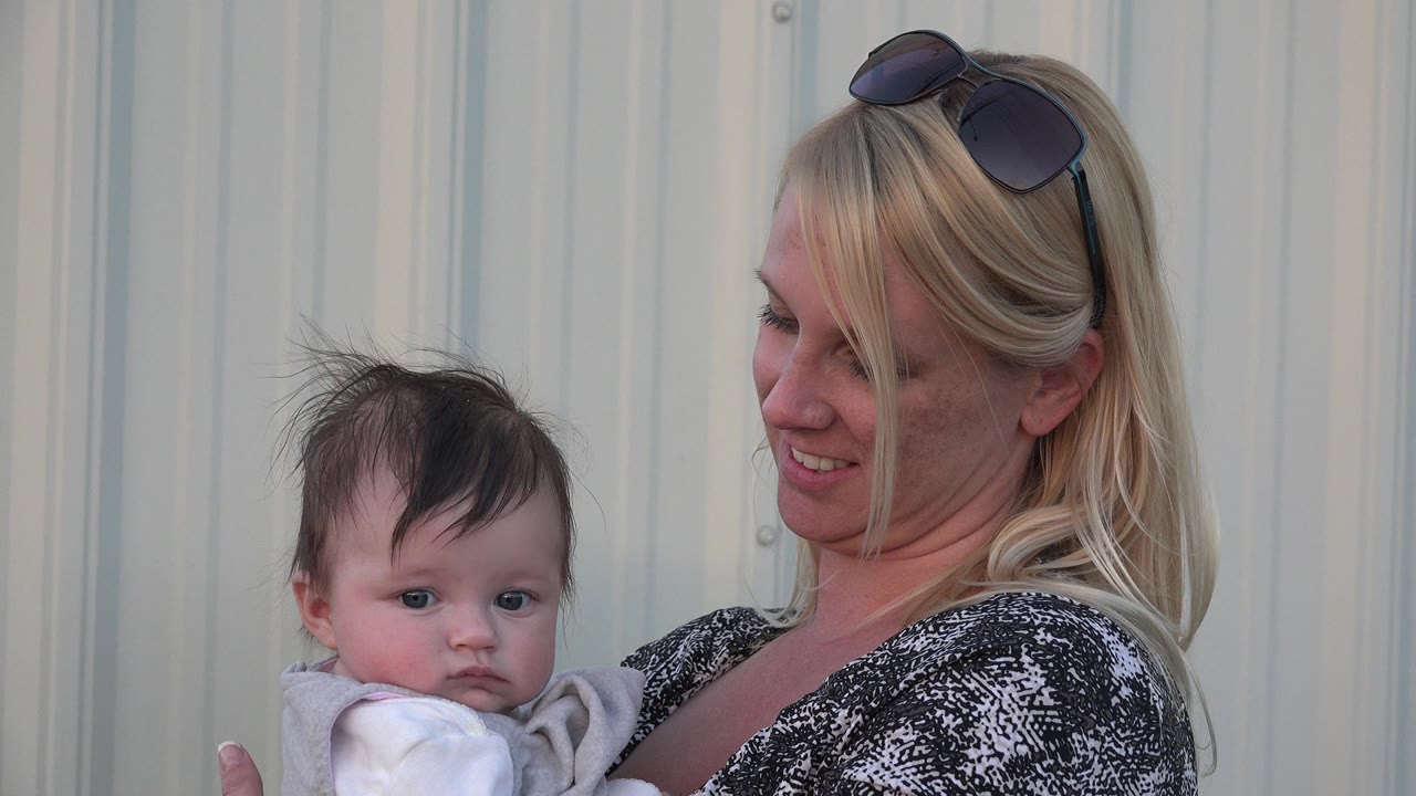 In Denver, Colorado, the baby faces closer toward the camera while the woman smiles and looks down toward the child against the same light wall.