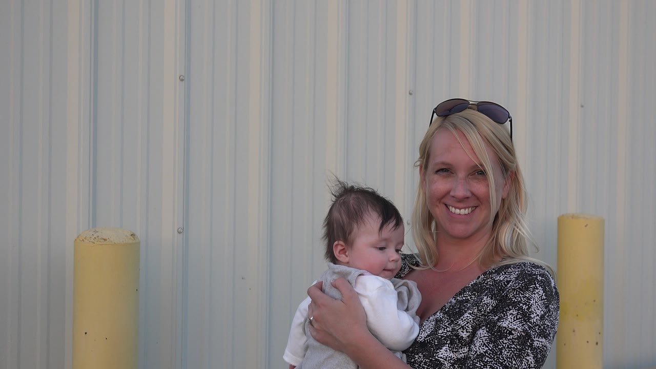 Woman holding baby as the child turns slightly sideways.