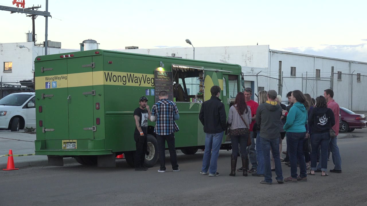 Small group gathered beside a green truck on a street.