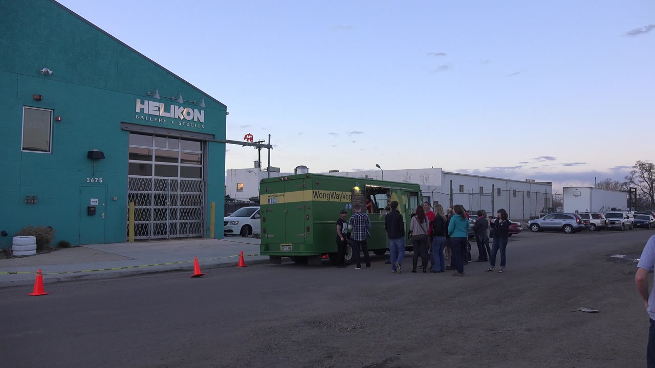 Small crowd near a green truck outside a teal building