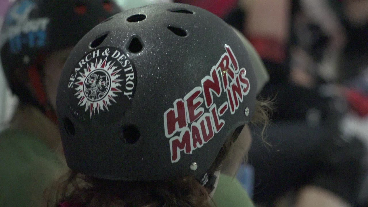 Close view of a black helmet with red and white lettering among other helmeted people.