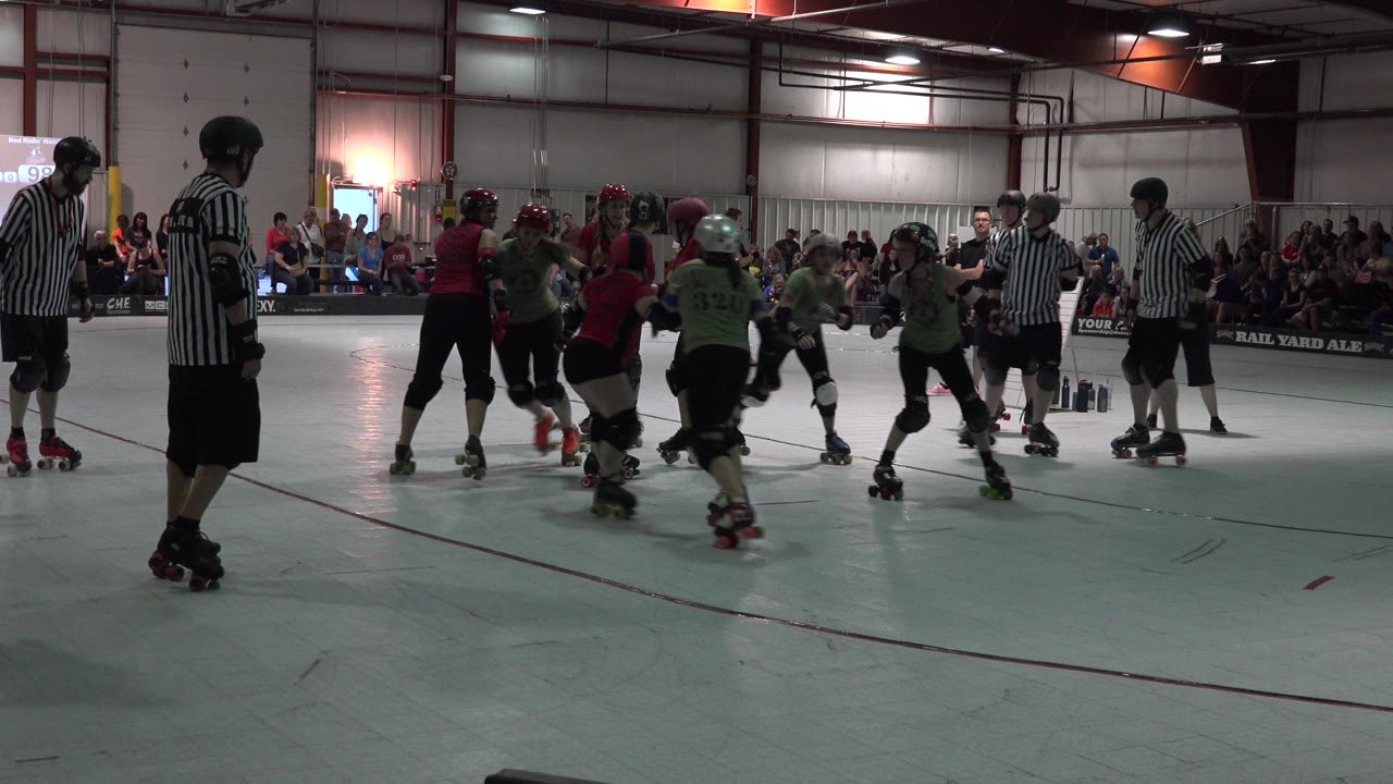 Roller derby skaters and referees on an indoor rink.