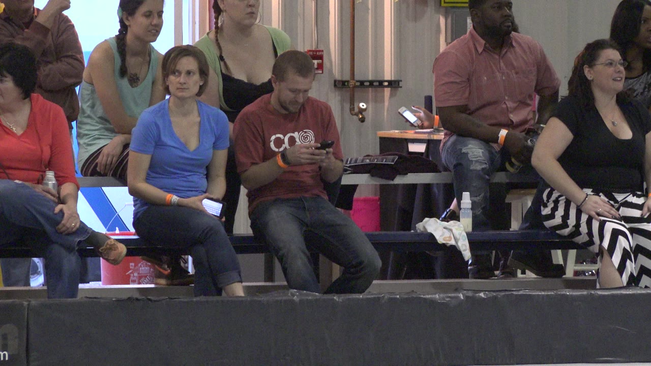 Adults seated on bleachers at an indoor roller rink.