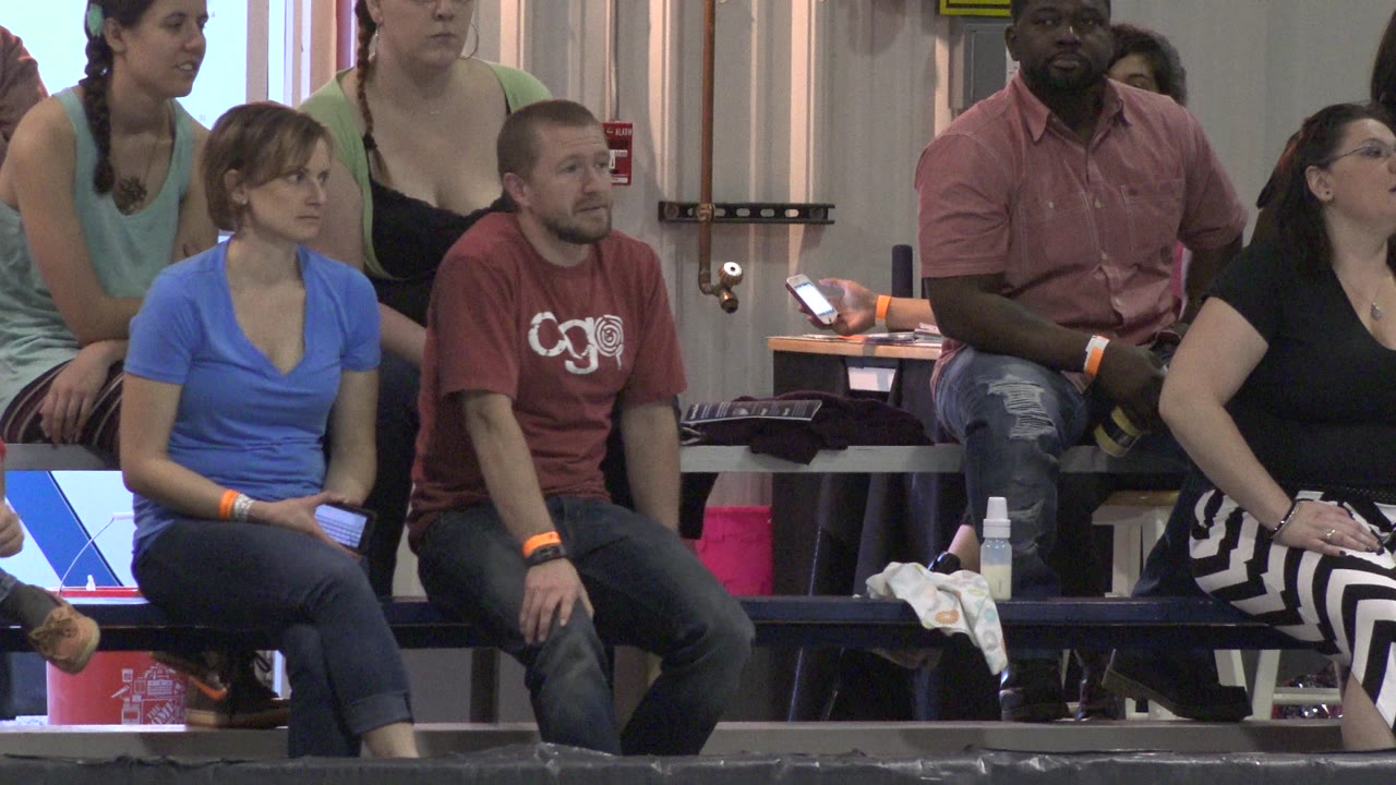 Group of adults watching from indoor stands.