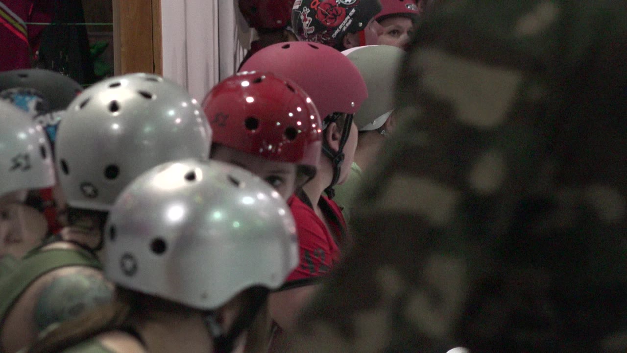 In Denver, Colorado, silver and red helmets fill the foreground as seated participants wait close together inside the venue.