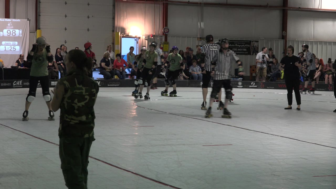 Denver rink scene with green-shirted roller skaters in the midground, referees in black-and-white stripes, seated spectators, and a bright projected score display in the background.
